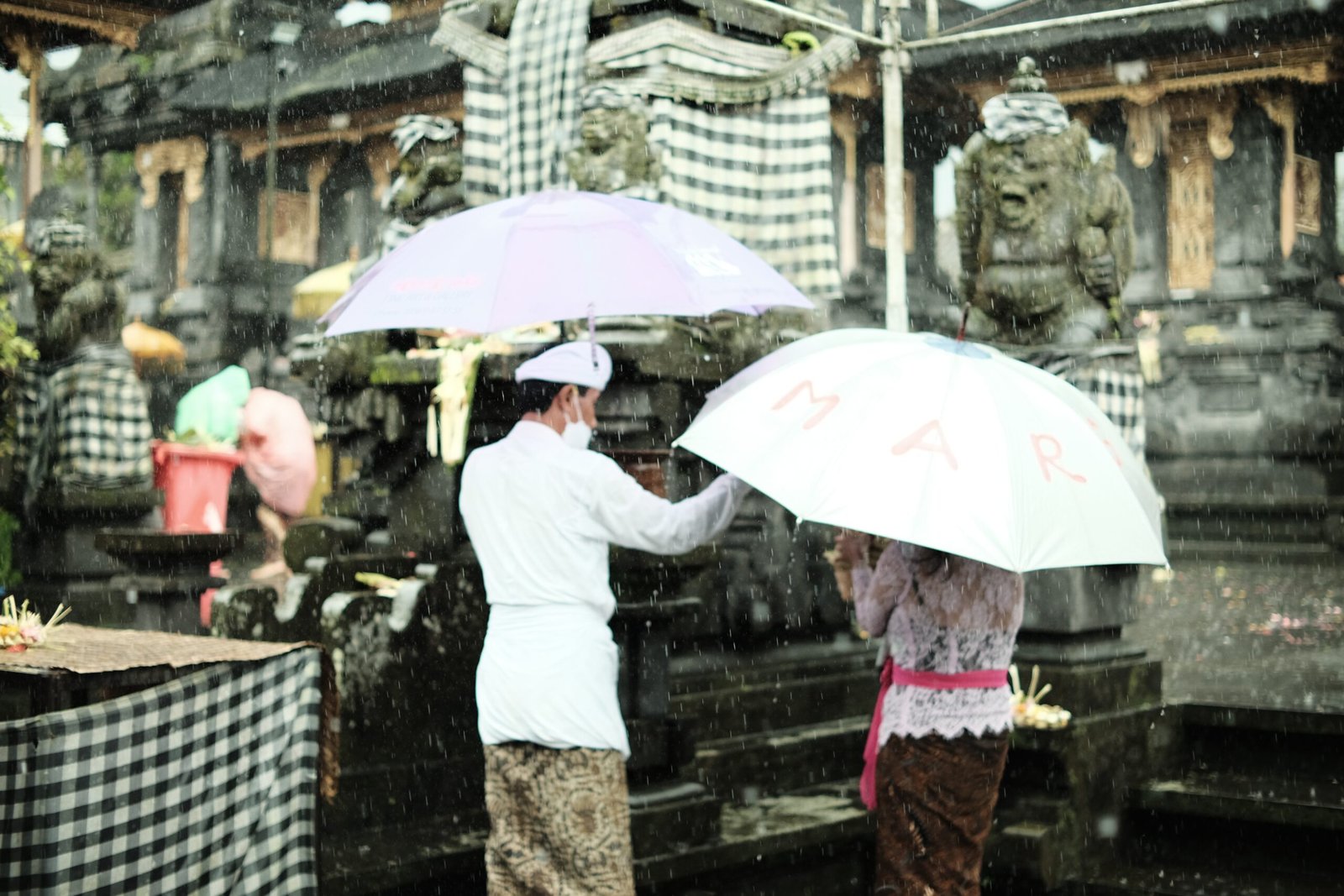 a couple of people standing under umbrellas in the rain